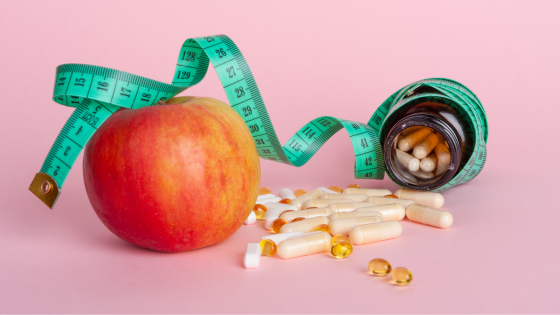 An apple, measuring tape, and diet pills